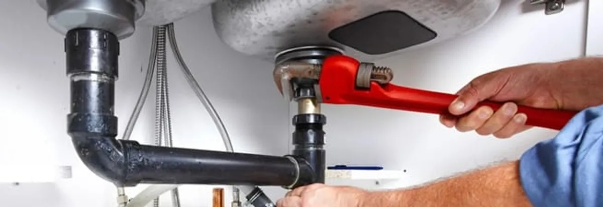 Garbage disposal repair technician tightening the sink drain and disposal connection in Philadelphia, PA