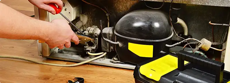Refrigerator repair technician fixing the compressor and wiring in Philadelphia, PA